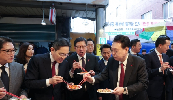 윤석열 대통령(사진 오른쪽 두 번째)이 국제시장을 방문해서 박형준 부산시장(왼쪽 세 번째), 이재용 삼성전자 회장(왼쪽 두 번째), 조현준 효성그룹 회장(왼쪽 첫 번째), 구광모 LG그룹 회장(오른쪽 두 번째), 김동관 한화그룹 부회장(맨 오른쪽)과 떡복이를 시식하고 있다.
