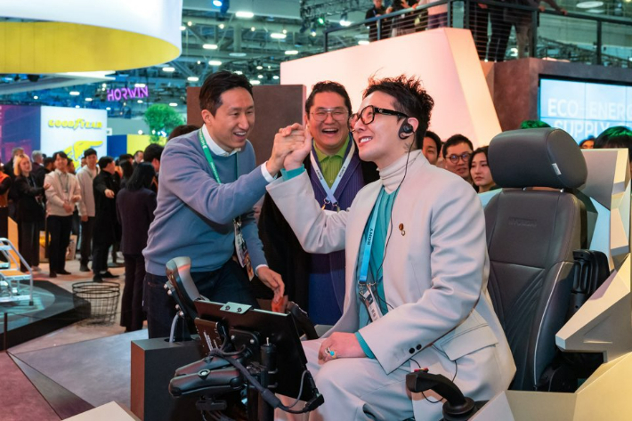 9일(현지시각) 'CES 2024' HD현대 부스를 방문한 지드래곤이 시뮬레이터에 탑승해 휠로더를 운전하며 HD현대 정기선 부회장과 하이파이브를 하고 있다. [HD현대 제공]