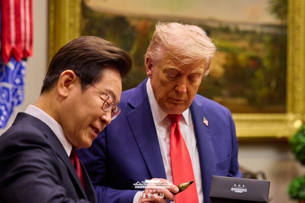 도널드 트럼프 대통령이 지난 25일(현지 시각) 백악관에서 열린 한미 정상회담에서 이재명 대통령이 선물한 서명용 펜을 유심히 들여다보고 있다 [대통령실 제공]