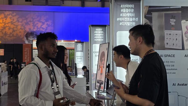 부산 벡스코에서 열린  아시아 스타트업 페스티벌인 'FLY ASIA 2025'에서 외국인 참가자가 굳갱랩스의 AI 아바타 가이드에 대한 설명을 듣고 있다. [사진=굳갱랩스]