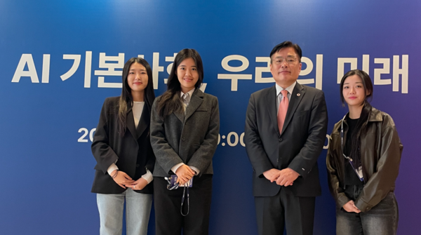 상명대학교 AR·VR미디어디자인전공 학생들과 장성각 충남콘텐츠진흥원 사업총괄실장이 'JTBC 투모로우 포럼 2025' 행사장의 'AI 기본사회, 우리의 미래' 슬로건 앞에서 기념 촬영을 하고 있다.[상명대학교 제공]