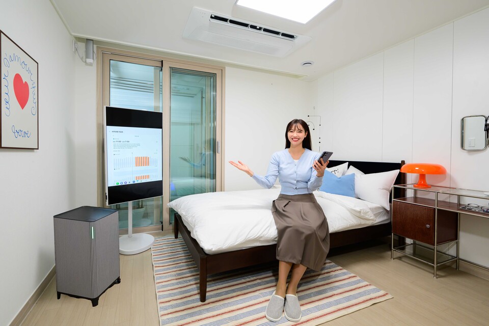 삼성전자 모델이 침실로 꾸며진 전시 공간에서 '취침 루틴' 설정, '수면 환경 리포트' 등 편안한 수면 환경을 제공하는 기능을 소개하고 있다. [삼성전자 제공]