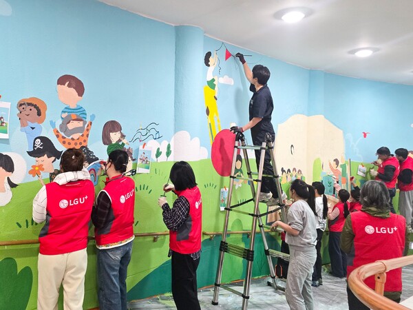 LG유플러스 임직원들이 충주성모학교 담장에 벽화를 그리고 있는 모습 [LG유플러스 제공]