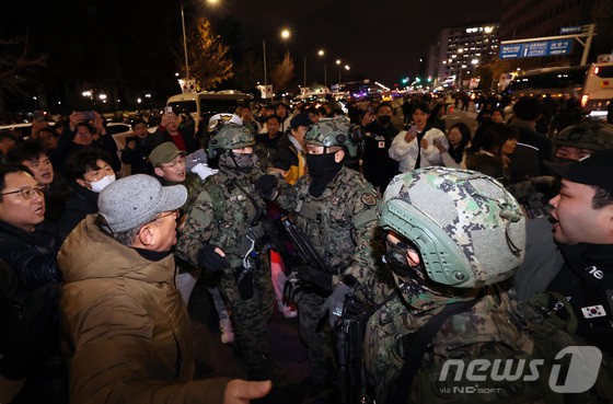 윤석열 대통령이 비상계엄령을 전격 선포한 가운데 4일 새벽 서울 여의도 국회 앞에서 시민들이 경내로 진입하려는 계엄군을 붙잡아 막아서고 있다.